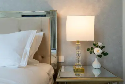 a bed with a lamp and a table with a vase of flowers at Ultimate Stay Port de La Mer with Burj Khalifa Views from the Bed next to the Beach in Dubai