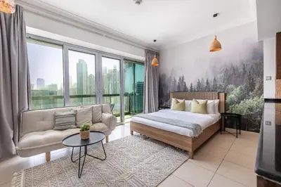 a bedroom with a bed and a couch and windows at Spacious Studio in Downtown I 8 Boulevard Walk in Dubai