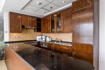 a kitchen with wooden cabinets and a black counter top at Spacious Studio in Downtown I 8 Boulevard Walk in Dubai