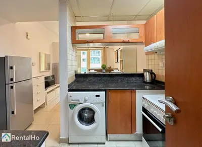 a kitchen with a washing machine in the middle at Quiet Studio with Balcony and Roof Top Pool in Dubai Marina in Dubai