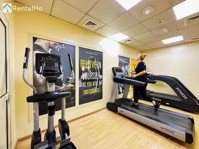 a woman running on a treadmill in a gym at Quiet Studio with Balcony and Roof Top Pool in Dubai Marina in Dubai