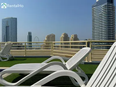 two white chairs sitting on a balcony with buildings at Quiet Studio with Balcony and Roof Top Pool in Dubai Marina in Dubai