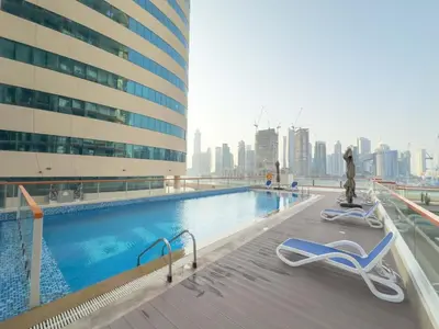 a swimming pool with two chairs and a building at AWS Holiday Homes - Luxurious 2BR in Business Bay in Dubai
