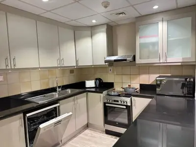 a kitchen with white cabinets and black counter tops at La buena vida holiday homes - Deluxe 3 bedroom apartment on the beach in Dubai