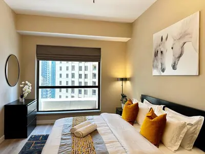 a bedroom with a large bed with a large window at La buena vida holiday homes - Deluxe 3 bedroom apartment on the beach in Dubai