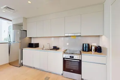 a kitchen with white cabinets and a stainless steel refrigerator at Sunset at Creek Beach - Exquisite Two Bedroom in Dubai