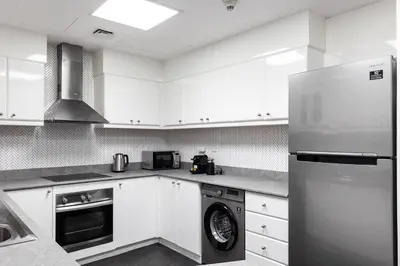 a kitchen with white cabinets and a stainless steel refrigerator at 2 BDR in Marina Terrace Dubai Marina in Dubai