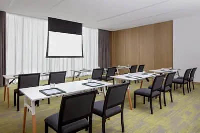 a conference room with tables and chairs and a screen at Holiday Inn Dubai Business Bay by IHG in Dubai