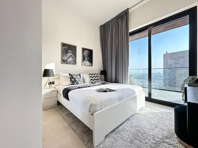 a bedroom with a white bed and a large window at Trophy Sunny Honey Suite Canal View & Infinty Pool in Dubai
