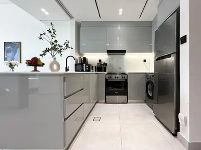 a white kitchen with a stove and a dishwasher at Trophy Sunny Honey Suite Canal View & Infinty Pool in Dubai