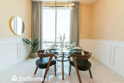 a dining room with a glass table and two chairs at 2ndHome - Amna Tower, Al Habtoor City in Dubai
