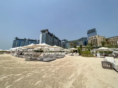 a beach with white chairs and umbrellas and buildings at Chic Palm Studio with Sea View & Infinity Pool in Dubai