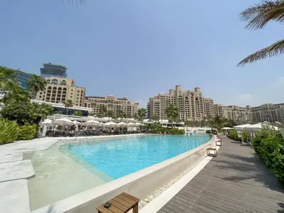 a swimming pool with chairs and buildings in the background at Chic Palm Studio with Sea View & Infinity Pool in Dubai