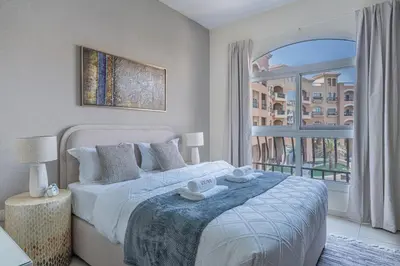 a bedroom with a bed and a large window at Stunning 1 BR Apartment with Pool View in JVC Dubai in Dubai