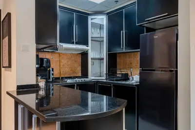 a kitchen with black cabinets and a black refrigerator at Stunning 1 BR Apartment with Pool View in JVC Dubai in Dubai