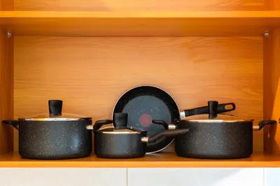 four pots and pans sitting on a wooden shelf at Furnished Apartment for Rent in Saba 3, JLT in Dubai