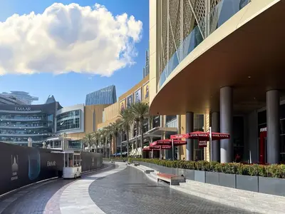 a street in a shopping center with palm trees and buildings at Trophy - Downtown Skyview Residence in 35th floor in Dubai
