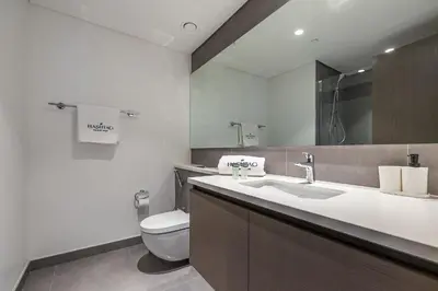 a bathroom with a toilet and a sink and a mirror at Spacious 3BDR with Maid Room I Creek Harbour I Creek Gate Tower 2 in Dubai