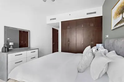 a bedroom with a white bed with a wooden headboard at StoneTree - Marina Tower 1BR - Dubai Marina in Dubai
