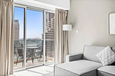 a living room with a couch and a large window at StoneTree - Marina Tower 1BR - Dubai Marina in Dubai