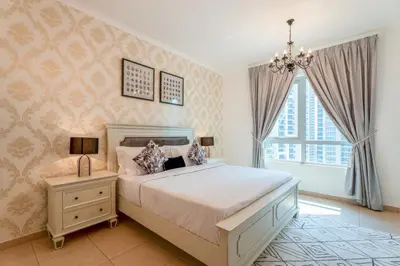 a bedroom with a large bed and a chandelier at INA HOMES - Residences Tower 1 Upper Floor in Dubai