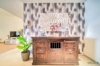 a wooden cabinet in a living room with a plant at Pristine 2BR at Bahar 2 JBR by Deluxe Holiday Homes in Dubai
