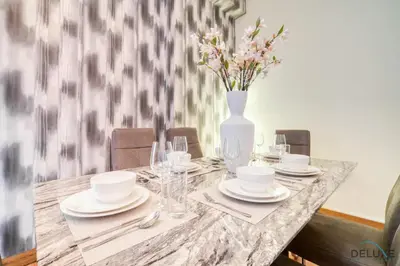 a dining table with plates and a vase with flowers at Pristine 2BR at Bahar 2 JBR by Deluxe Holiday Homes in Dubai