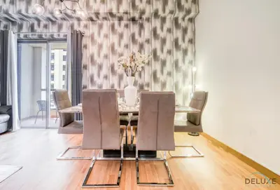 a dining room table with chairs and a vase of flowers at Pristine 2BR at Bahar 2 JBR by Deluxe Holiday Homes in Dubai