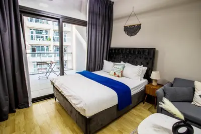 a bedroom with a bed and a couch and a window at Modern Silicon Oasis Studio Near Academic City in Dubai