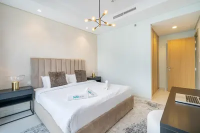 a bedroom with a large white bed with a desk at Stylish 2Bedroom w infinity pool on the 64th floor in Dubai