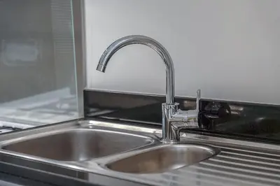 a stainless steel kitchen sink with a faucet at Floral Charm studio in Damac Hills by Suiteable in Dubai