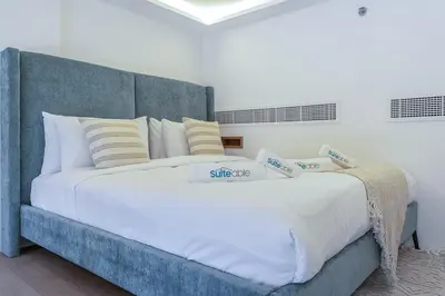 a large bed with white sheets and pillows at Relax & Recharge Studio Loft with hanging net in Dubai