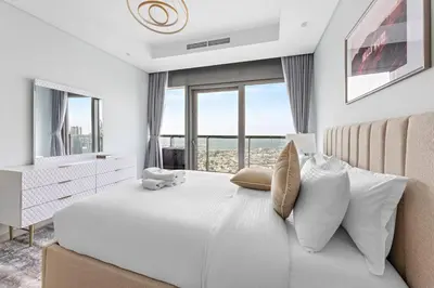 a white bedroom with a large white bed with windows at StoneTree - Paramount 3BR - Panoramic View in Dubai