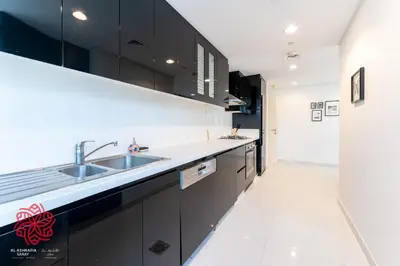 a kitchen with black cabinets and a sink at Alashrafia Saray- Waterfront 3 BDR apartment Business Bay in Dubai