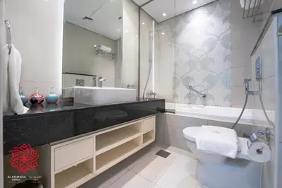 a bathroom with a sink and a toilet and a mirror at Alashrafia Saray- Waterfront 3 BDR apartment Business Bay in Dubai