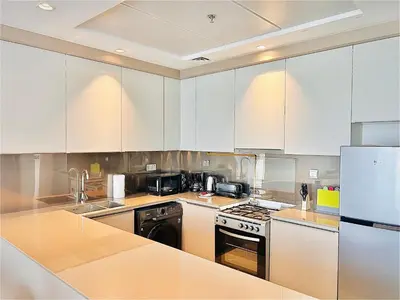 a kitchen with white cabinets and a stove top oven at Modern 1 BR Apartment at JVC Dubai Prime Location! in Dubai