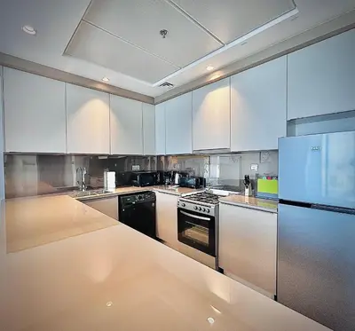 a kitchen with white cabinets and a stove and refrigerator at Modern 1 BR Apartment at JVC Dubai Prime Location! in Dubai