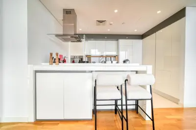 a kitchen with white cabinets and two stools at a counter at Bluewaters Residences - Sea View, Bluewaters Island - Mint Stay in Dubai