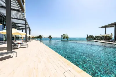 a pool with chairs and umbrellas next to the water at Bluewaters Residences - Sea View, Bluewaters Island - Mint Stay in Dubai