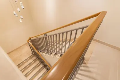 a staircase with a wooden rail and a metal railing at Chic 2BR Duplex, Huge Balcony High-End Furniture - Allsopp&Allsopp in Dubai