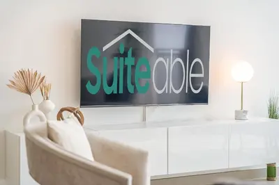 a living room with a tv on a white wall at Sunset spot with breathtaking view by Suiteable in Dubai