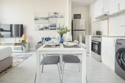 a white kitchen with a table and chairs in it at Frank Porter - Square Tower in Dubai