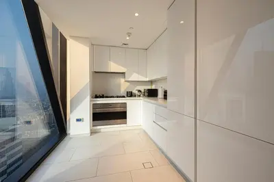a kitchen with white cabinets and a large window at Magnificent 3BR Spectacular Canal & Burj View in Dubai