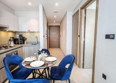 a dining room table with blue chairs and a kitchen at STAY BY LATINEM Luxury 1BR Holiday Home W1006 near Burj Khalifa in Dubai