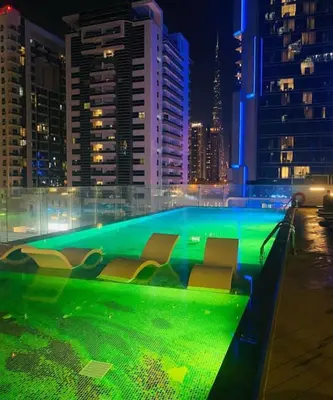 a swimming pool with chairs in a city at night at Chez Fouzia in Dubai