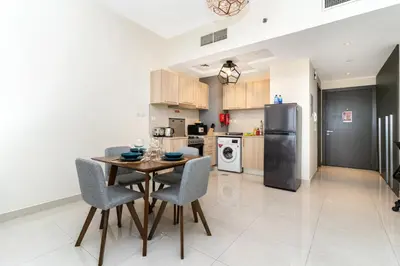 a kitchen with a table and chairs and a refrigerator at Elegant Studio in City Center with Balcony in Dubai