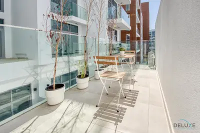 a balcony with potted plants and a table on a building at Upbeat 1BR at Pantheon Elysee Jumeirah Village Circle by Deluxe Holiday Homes in Dubai