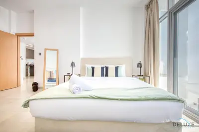a bedroom with a large white bed and a large window at Upbeat 1BR at Pantheon Elysee Jumeirah Village Circle by Deluxe Holiday Homes in Dubai