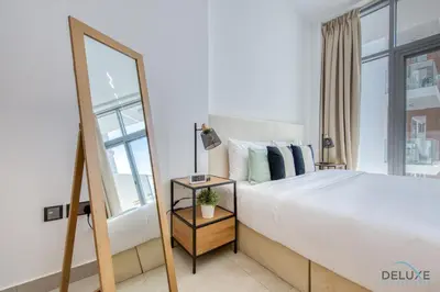 a bedroom with a large bed and a mirror at Upbeat 1BR at Pantheon Elysee Jumeirah Village Circle by Deluxe Holiday Homes in Dubai