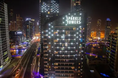a tall building with the words snake towers lit up at night at Shams Apart on JBR - 1 Bedroom - Marina View in Dubai